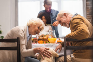 elderly-couple-petting-yellow-lab-dog-while-waiting-for-turkey-dinner